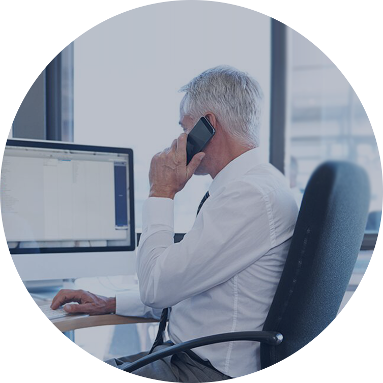 A man sits at a desk talking on a cell phone