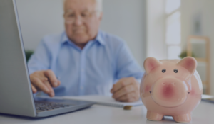 life insurance and annuities - older man on computer with a piggy bank next to him